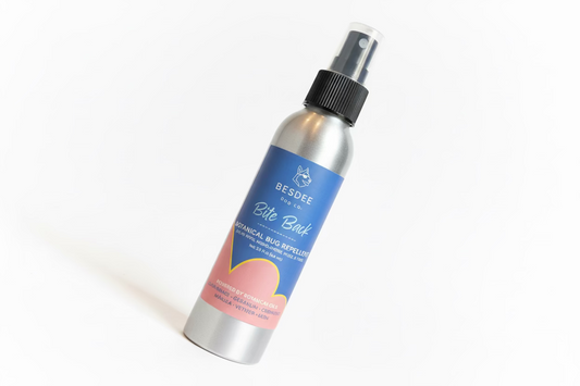 Bottle of Besdee Bite Back botanical bug repellent on a colorful surface with a blurred background
